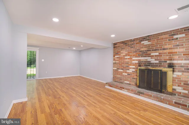 a view of empty room with wooden floor and fireplace