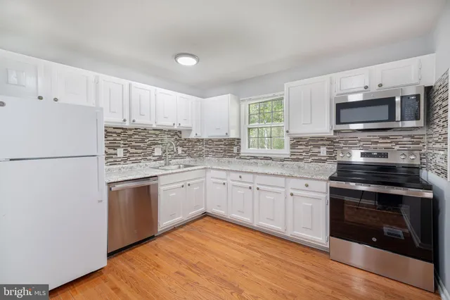 a kitchen with stainless steel appliances granite countertop a stove top oven a sink and a refrigerator