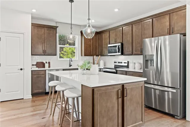 a kitchen with stainless steel appliances kitchen island granite countertop a stove a sink a microwave a island with a dining table and chairs