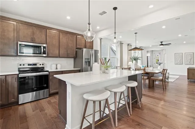 a room with stainless steel appliances kitchen island granite countertop a table chairs and a sink