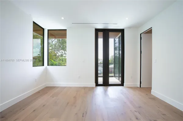 an empty room with wooden floor and windows