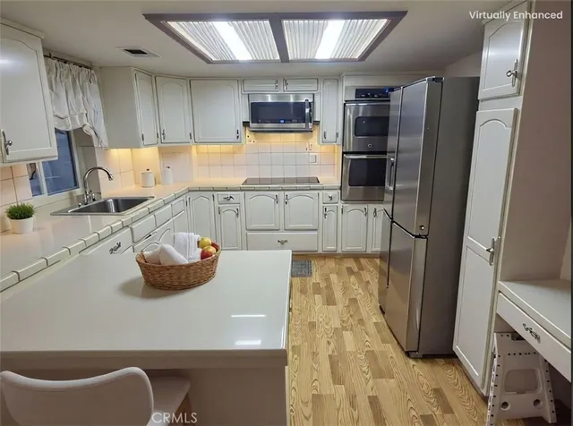 a kitchen with stainless steel appliances wooden floor and a refrigerator