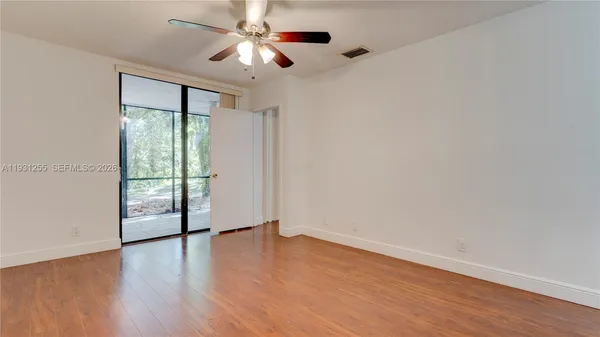 an empty room with wooden floor fan and windows