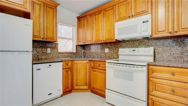 a kitchen with stainless steel appliances granite countertop white cabinets sink and a granite counter top