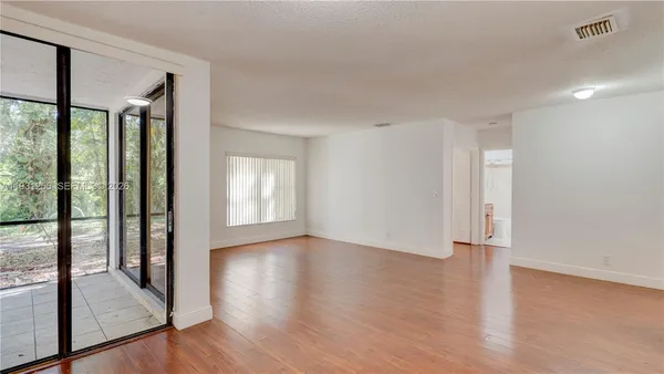a view of an empty room with wooden floor and a window