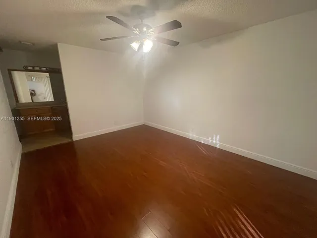 an empty room with a ceiling fan and wooden floor