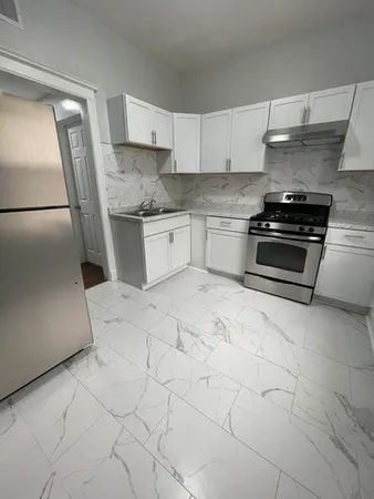 a kitchen with granite countertop a stove a sink and a refrigerator
