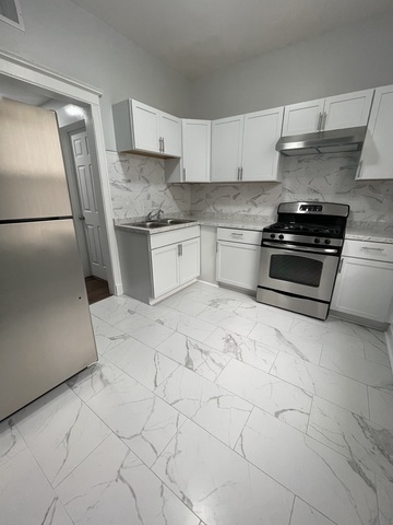 916 West 68th Street, Unit 2W Chicago, IL 60621 - Photo 5 of 8 a kitchen with granite countertop a stove a sink and a refrigerator