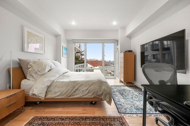 a bedroom with a bed wooden floor and windows