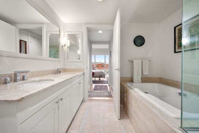 a spacious bathroom with a tub sink and mirror