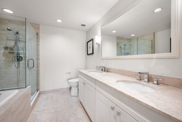 a bathroom with a granite countertop sink a toilet and shower