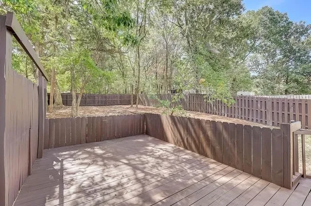 a view of a backyard with wooden fence and a large tree