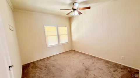 an empty room with windows and fan
