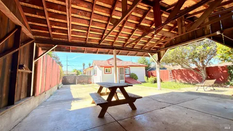 a view of a backyard with large trees and wooden fence