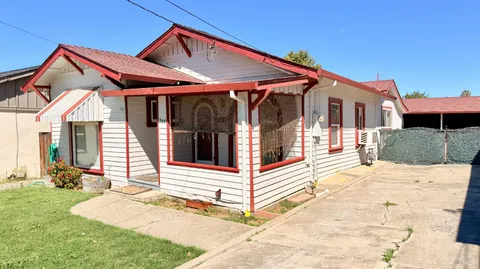 a view of wooden house with a yard and lawn chairs