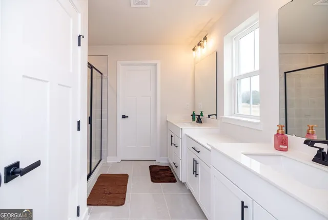 a spacious bathroom with a double vanity sink a mirror a shower and a bathtub