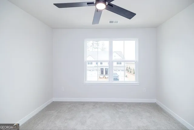 an empty room with a window and a fan