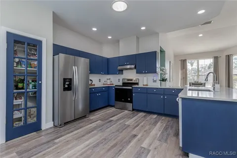 a kitchen with stainless steel appliances granite countertop a refrigerator cabinets and wooden floor
