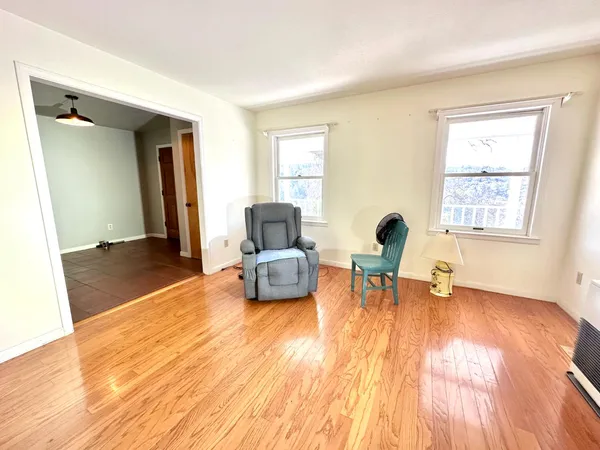 an empty room with wooden floor fireplace and windows