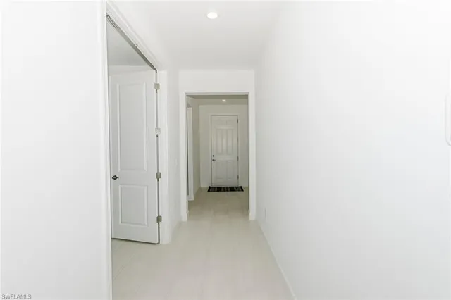 a view of kitchen with refrigerator and white cabinets