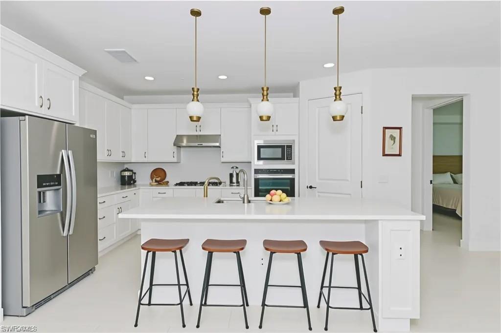 1954 Fresno Avenue Naples, FL 34120 - Photo 6 of 40 a kitchen with stainless steel appliances a refrigerator a sink and white cabinets