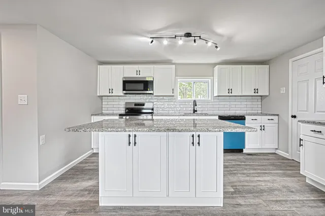 a kitchen with granite countertop a sink and a stove top oven