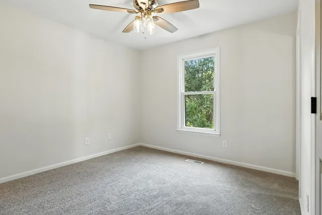 an empty room with a window and a fan