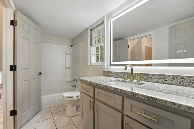 a bathroom with a granite countertop sink a mirror and a toilet
