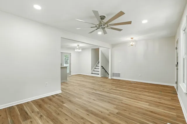 a view of an empty room with wooden floor and a ceiling fan