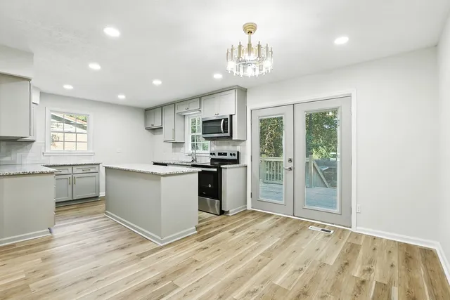 a kitchen with granite countertop a refrigerator and white cabinets
