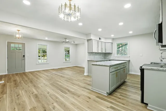 a large kitchen with stainless steel appliances granite countertop a stove oven a sink dishwasher and a refrigerator with wooden floor