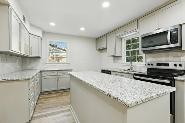 a kitchen with stainless steel appliances granite countertop a sink stove and microwave