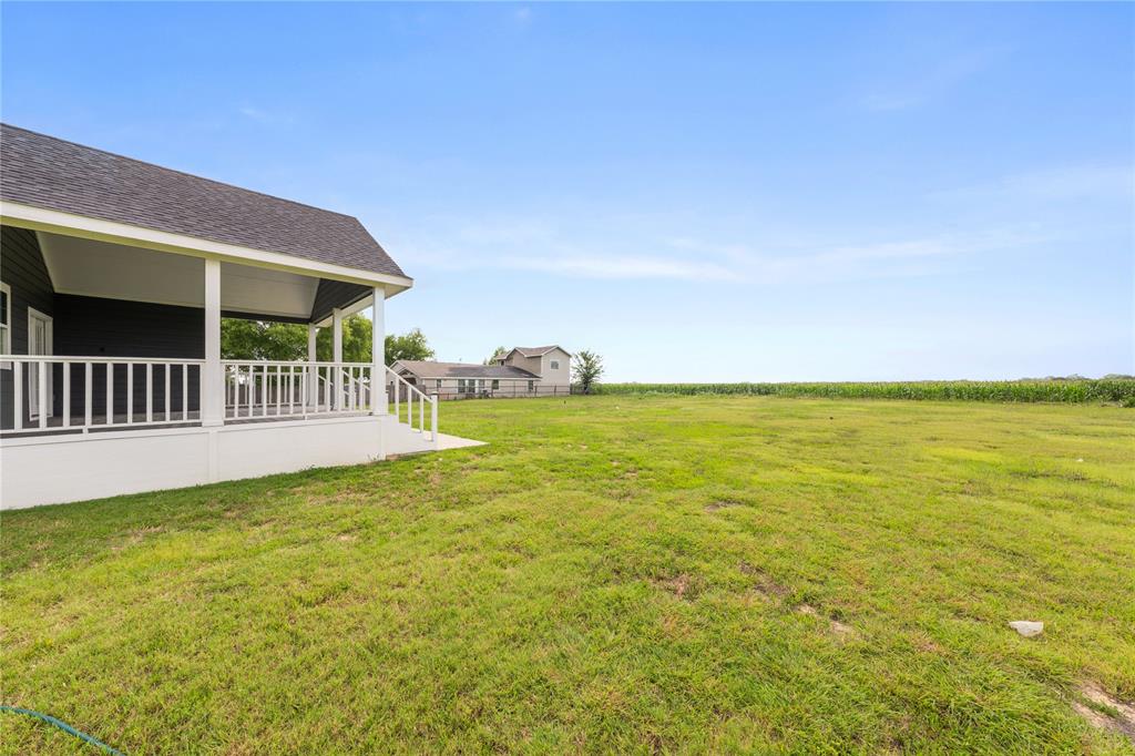 1128 Newton Road Ferris, TX 75125 - Photo 28 of 28 Rear exterior featuring a covered porch with white railing, dark siding, and a gabled roofline