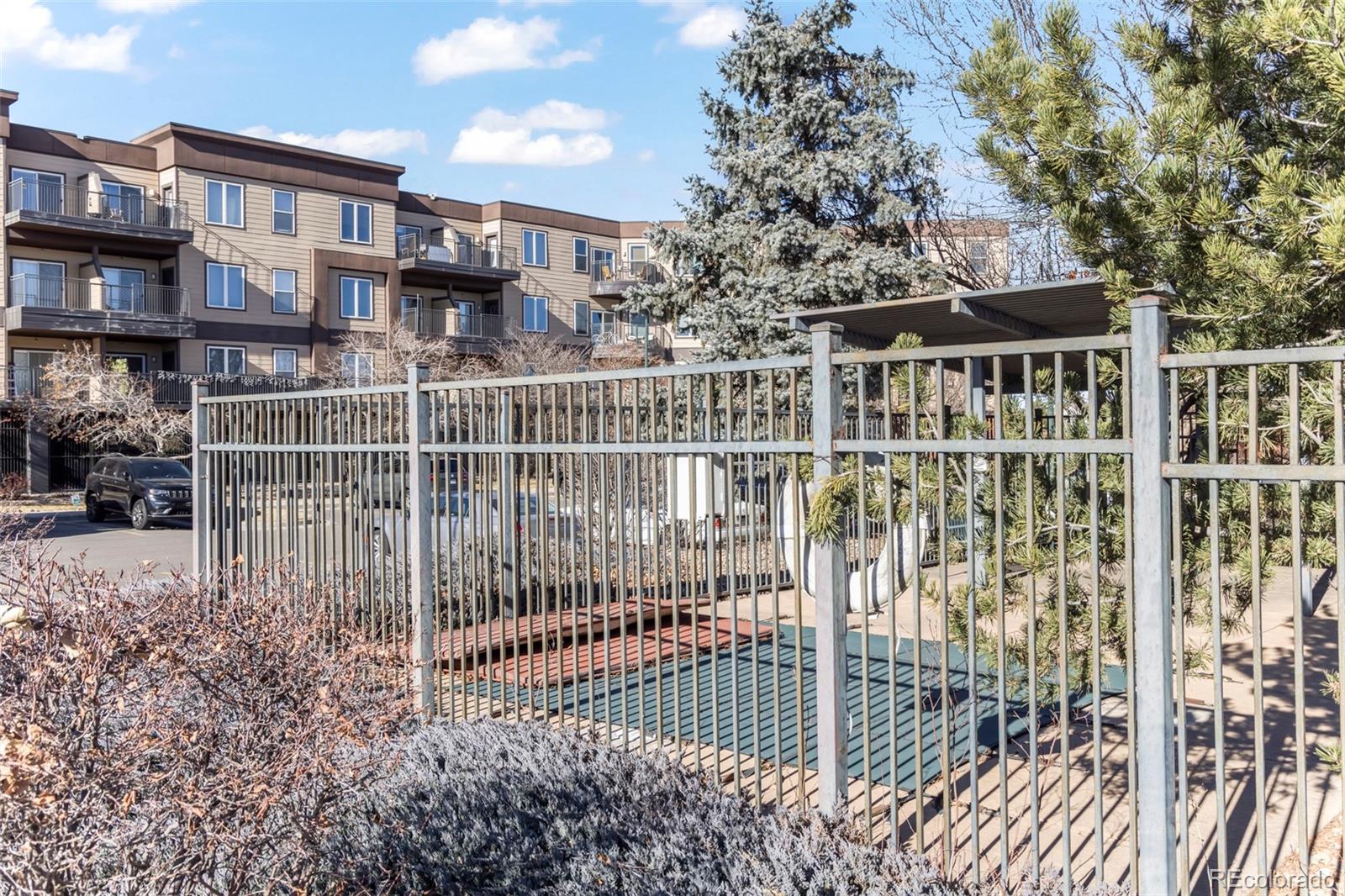 15475 Andrews Drive, Unit 307 Denver, CO 80239 - Photo 35 of 36 a view of a building with a small yard and wooden fence