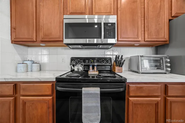 a kitchen with granite countertop a stove top oven microwave and cabinets