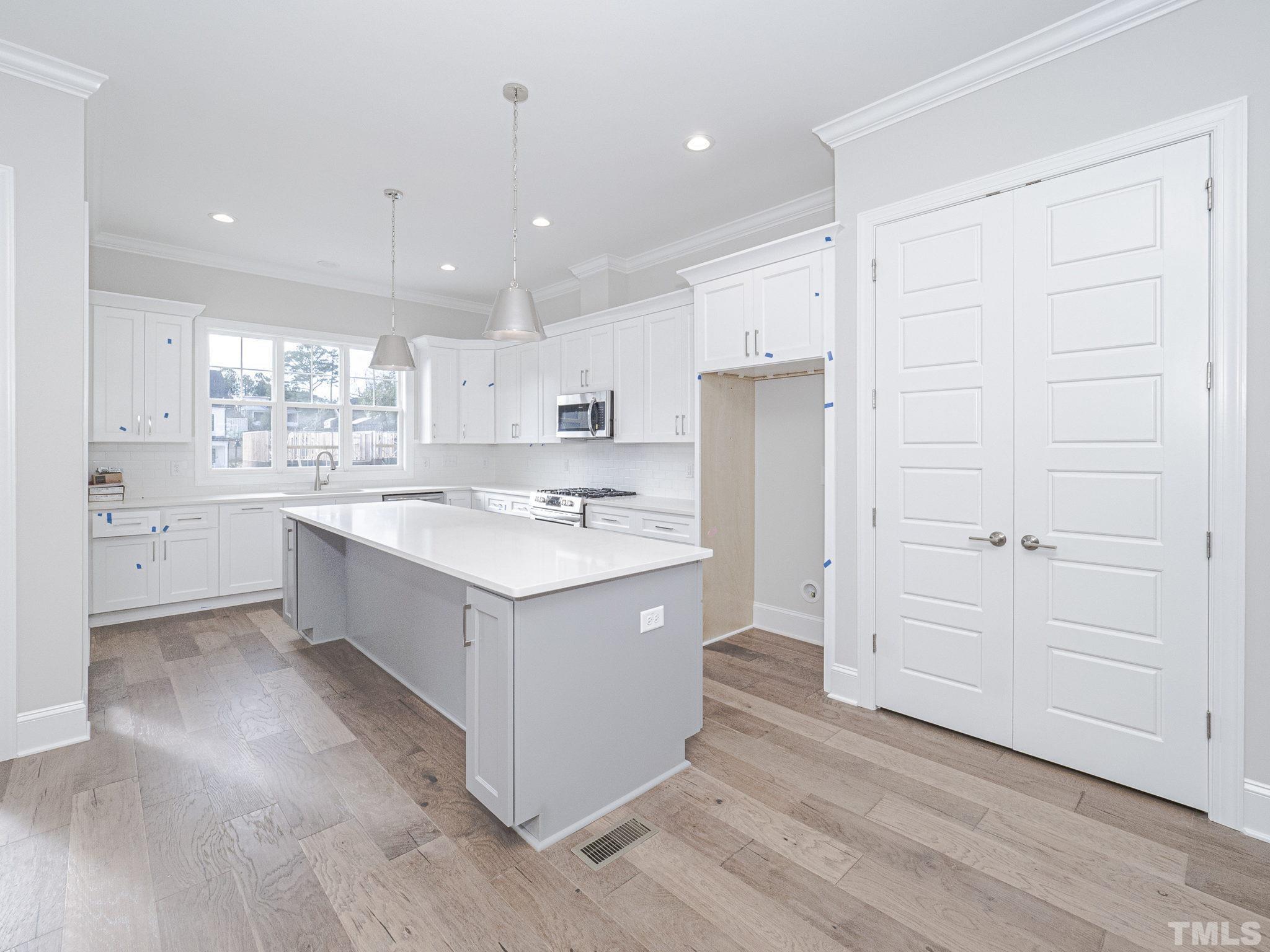 4922 Trek Lane Raleigh, NC 27606 - Photo 11 of 28 a large kitchen with a large counter top a sink stainless steel appliances and cabinets