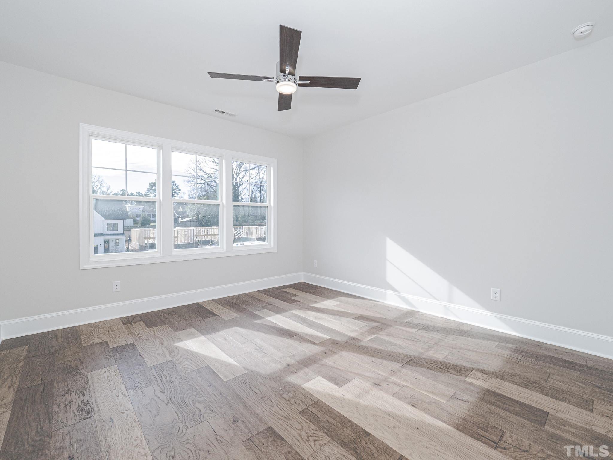 4922 Trek Lane Raleigh, NC 27606 - Photo 20 of 28 an empty room with wooden floor fan and windows