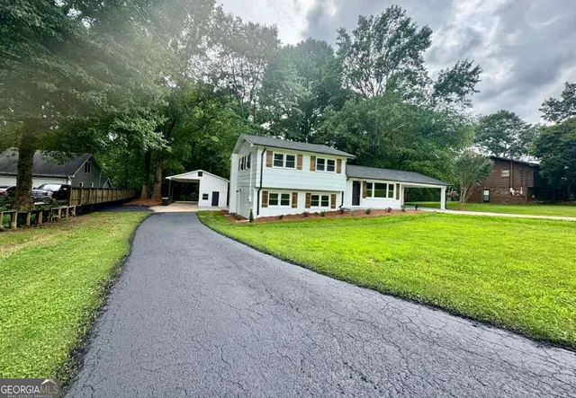 a view of a house with a big yard and large trees