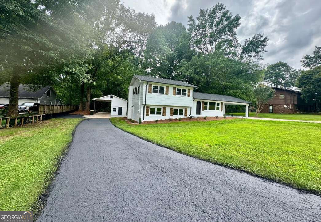 a view of a house with a big yard and large trees