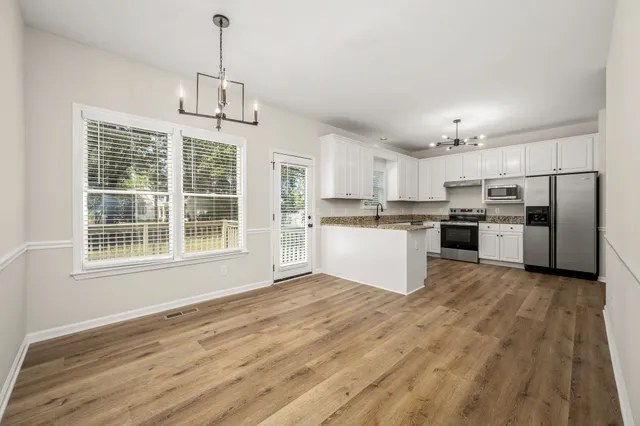 a view of kitchen with granite countertop stainless steel appliances a refrigerator cabinets and wooden floor