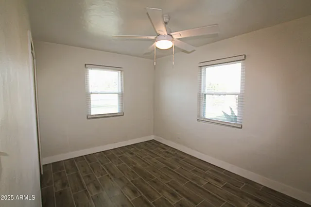 an empty room with wooden floor fan and windows