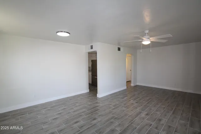 an empty room with wooden floor and a ceiling fan