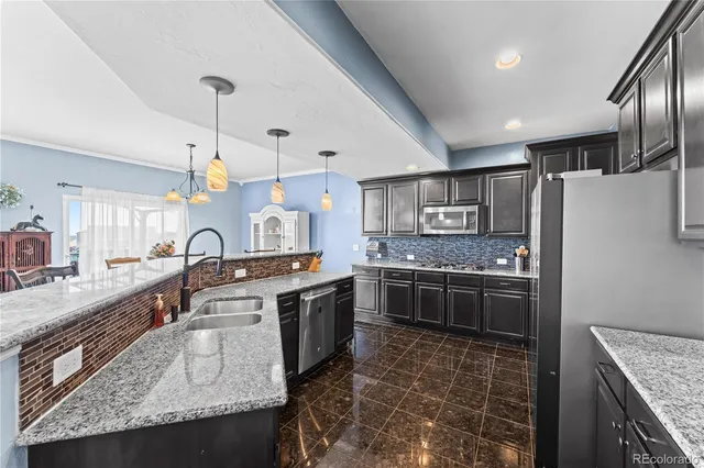 a large kitchen with stainless steel appliances granite countertop a stove top oven a refrigerator a sink and dishwasher