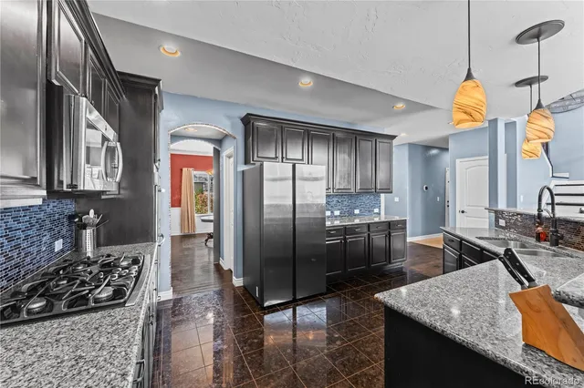a kitchen with stainless steel appliances granite countertop a sink a stove and a refrigerator