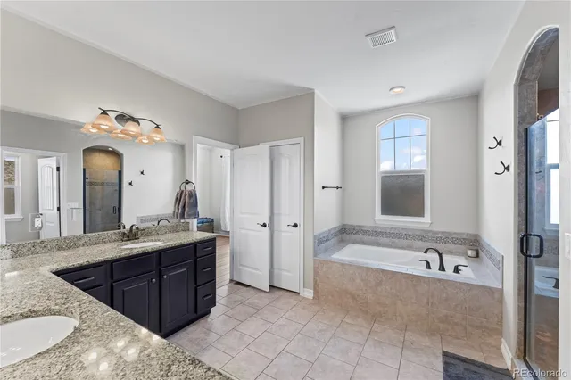 a spacious bathroom with a granite countertop double vanity sink mirror and bathtub
