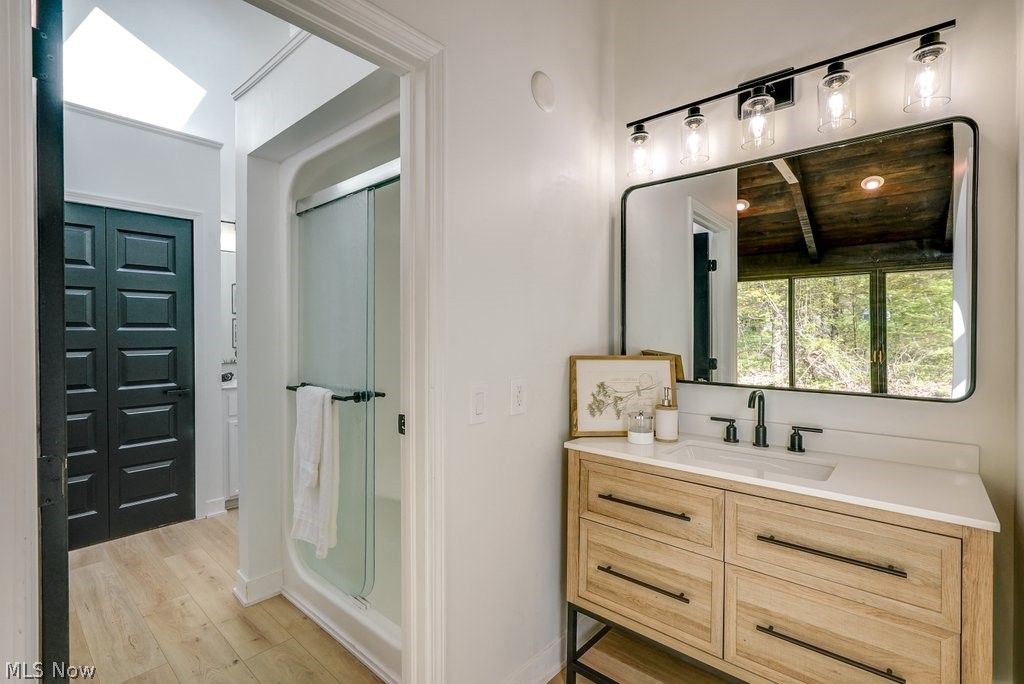 8108 Stone Road Independence, OH 44131 - Photo 19 of 38 Bathroom featuring vaulted ceiling with beams, wood-type flooring, vanity, a shower with door, and wooden ceiling