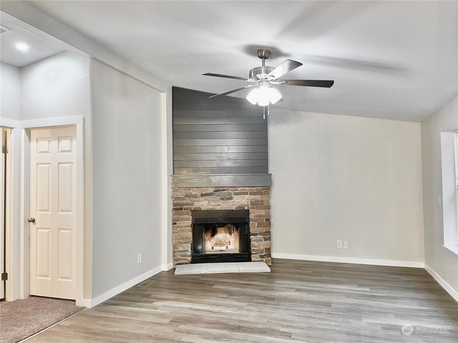 125 Hackett Road Longview, WA 98632 - Photo 11 of 34 a view of an empty room with wooden floor a ceiling fan and a fireplace