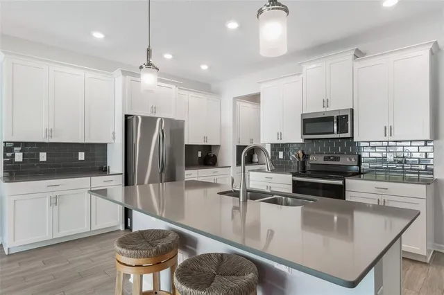 a kitchen with stainless steel appliances granite countertop a sink a stove a refrigerator and island with wooden floor