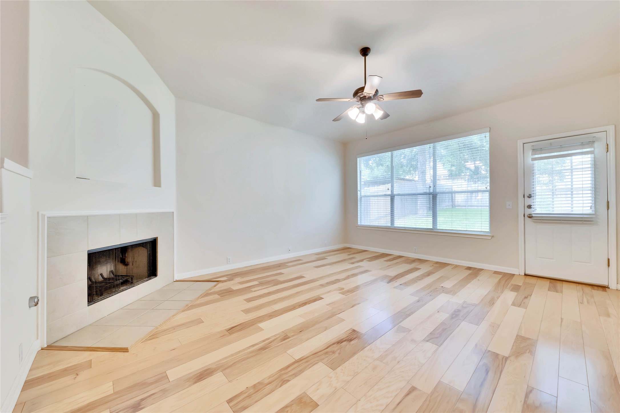 2133 Paradise Ridge Drive Round Rock, TX 78665 - Photo 13 of 22 Spacious room featuring wood-finish flooring, a fireplace with tile surround, a large window, a ceiling fan, and access to the exterior