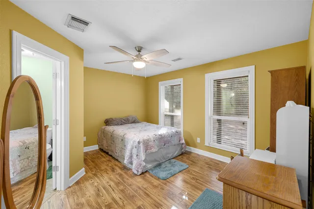 a spacious bedroom with a bed a dresser and a large window